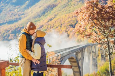 Montenegro. Happy couple man and woman in background of Dzhurdzhevich Bridge Over The River Tara foggy morning. Travel around Montenegro concept. Sights of Montenegro