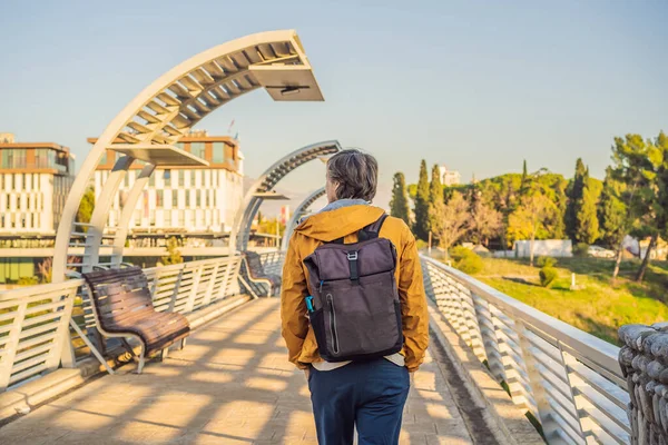 Man tourist on the background of the Moscow footbridge in Podgorica. The metal construction of this pedestrian bridge was a gift by the city of Moscow to the people of Montenegro. Built in 2008 the — ストック写真