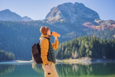 Kara Göl Crno Jezero 'nun panoramik sabah manzaralı arka planındaki erkek turist. Durmitor Nacionalni Park 'ın sakin yaz manzarası, Zabljak konumu, Karadağ, Avrupa. Doğa konseptinin güzelliği