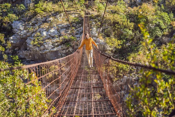 Turista en el viejo puente oxidado. Atracción Largo puente de hierro colgante extremo sobre el río Moraca. Monumentos de Montenegro. Monumento histórico Montenegro — Foto de Stock