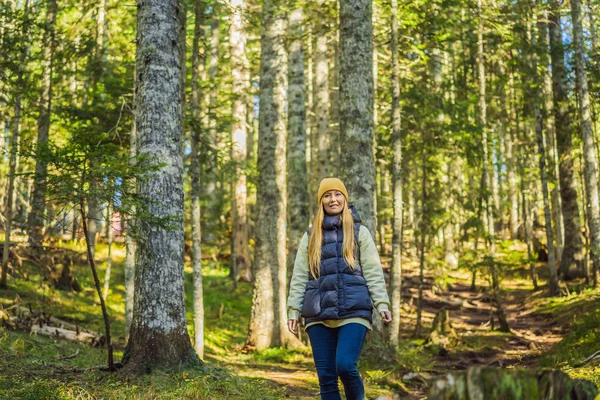 Une femme en vêtements chauds profite d'une promenade dans une forêt de pins — Photo