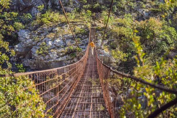 Man tourist on Old rusty bridge. Attraction Long extreme suspension iron bridge across the river Moraca. Sights of Montenegro. Landmark Montenegro — Stock Photo, Image