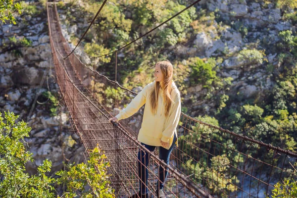 Woman tourist on Old rusty bridge. Attraction Long extreme suspension iron bridge across the river Moraca. Sights of Montenegro. Landmark Montenegro — 스톡 사진