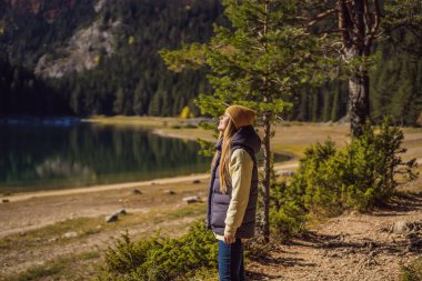 Kara Göl Crno Jezero 'nun Panoramik Sabah Görüşü' nün arka planındaki kadın turist. Durmitor Nacionalni Park 'ın sakin yaz manzarası, Zabljak konumu, Karadağ, Avrupa. Doğanın güzelliği konsepti