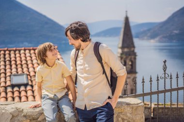 Baba ve oğul turistler güneşli bir günde Karadağ 'ın Eski Perast kasabasında renkli caddelerin tadını çıkarıyorlar. Karadağ 'a seyahat. Ünlü Kotor Körfezi 'ndeki tarihi Perast kasabasının manzara manzarası.