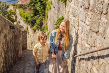Anne ve oğul turistler güneşli bir günde Karadağ 'ın Eski Perast kasabasında renkli caddelerin tadını çıkarıyorlar. Karadağ 'a seyahat. Ünlü Kotor Körfezi 'ndeki tarihi Perast kasabasının manzara manzarası.