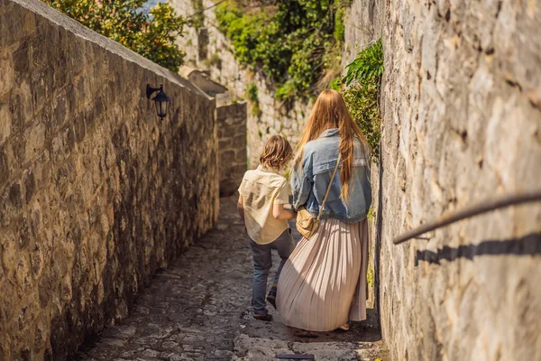 Mamma och son turister njuter av färgglada gatan i Gamla stan i Perast på en solig dag, Montenegro. Res till Montenegro konceptet. Natursköna panorama utsikt över den historiska staden Perast vid berömda Bay of Kotor — Stockfoto