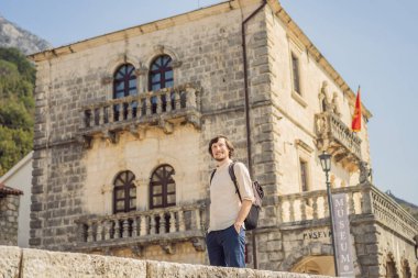 Eski Perast kasabasında güneşli bir günde Renkli caddenin tadını çıkaran erkek turist. Karadağ 'a seyahat. Ünlü Kotor Körfezi 'ndeki tarihi Perast kasabasının manzara manzarası