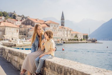 Anne ve oğul turistler güneşli bir günde Karadağ 'ın Eski Perast kasabasında renkli caddelerin tadını çıkarıyorlar. Karadağ 'a seyahat. Ünlü Kotor Körfezi 'ndeki tarihi Perast kasabasının manzara manzarası.