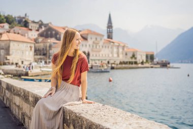 Karadağ 'ın eski Perast kasabasında güneşli bir günde Renkli Sokak' ta eğlenen kadın turist. Karadağ 'a seyahat. Ünlü Kotor Körfezi 'ndeki tarihi Perast kasabasının manzara manzarası