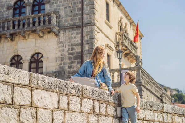 Mom and son tourists enjoying Colorful street in Old town of Perast on a sunny day, Montenegro. Travel to Montenegro concept. Scenic panorama view of the historic town of Perast at famous Bay of Kotor — Stock Photo, Image