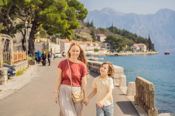 Mãe e filho turistas desfrutando de rua colorida na cidade velha de Perast em um dia ensolarado, Montenegro. Viajar para Montenegro conceito. Vista panorâmica panorâmica da cidade histórica de Perast na famosa Baía de Kotor — Fotografia de Stock