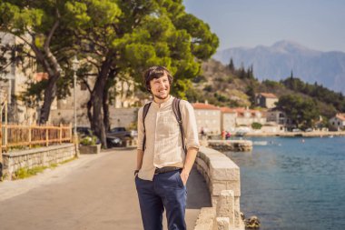 Eski Perast kasabasında güneşli bir günde Renkli caddenin tadını çıkaran erkek turist. Karadağ 'a seyahat. Ünlü Kotor Körfezi 'ndeki tarihi Perast kasabasının manzara manzarası