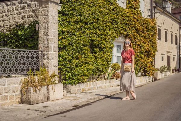 Karadağ 'ın eski Perast kasabasında güneşli bir günde Renkli Sokak' ta eğlenen kadın turist. Karadağ 'a seyahat. Ünlü Kotor Körfezi 'ndeki tarihi Perast kasabasının manzara manzarası — Stok fotoğraf