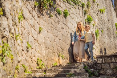 Anne ve oğul turistler güneşli bir günde Karadağ 'ın Eski Perast kasabasında renkli caddelerin tadını çıkarıyorlar. Karadağ 'a seyahat. Ünlü Kotor Körfezi 'ndeki tarihi Perast kasabasının manzara manzarası.