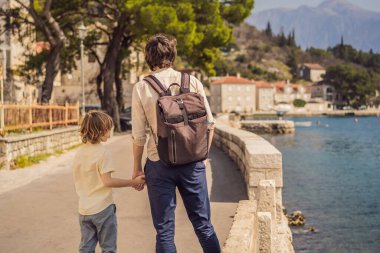 Baba ve oğul turistler güneşli bir günde Karadağ 'ın Eski Perast kasabasında renkli caddelerin tadını çıkarıyorlar. Karadağ 'a seyahat. Ünlü Kotor Körfezi 'ndeki tarihi Perast kasabasının manzara manzarası.