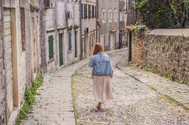 Ünlü Kotor Körfezi 'nde tarihi Risan kasabasının manzara manzarasının arka planındaki kadın turist güzel güneşli bir günde mavi gökyüzü ve bulutlarla yaz mevsiminde Karadağ, güney Avrupa.