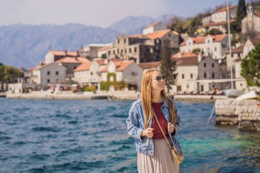 Karadağ 'ın eski Perast kasabasında güneşli bir günde Renkli Sokak' ta eğlenen kadın turist. Karadağ 'a seyahat. Ünlü Kotor Körfezi 'ndeki tarihi Perast kasabasının manzara manzarası