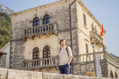 Eski Perast kasabasında güneşli bir günde Renkli caddenin tadını çıkaran erkek turist. Karadağ 'a seyahat. Ünlü Kotor Körfezi 'ndeki tarihi Perast kasabasının manzara manzarası