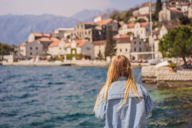 Karadağ 'ın eski Perast kasabasında güneşli bir günde Renkli Sokak' ta eğlenen kadın turist. Karadağ 'a seyahat. Ünlü Kotor Körfezi 'ndeki tarihi Perast kasabasının manzara manzarası