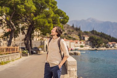 Eski Perast kasabasında güneşli bir günde Renkli caddenin tadını çıkaran erkek turist. Karadağ 'a seyahat. Ünlü Kotor Körfezi 'ndeki tarihi Perast kasabasının manzara manzarası