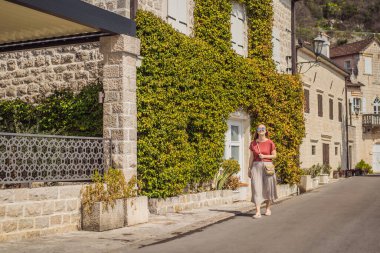 Karadağ 'ın eski Perast kasabasında güneşli bir günde Renkli Sokak' ta eğlenen kadın turist. Karadağ 'a seyahat. Ünlü Kotor Körfezi 'ndeki tarihi Perast kasabasının manzara manzarası