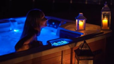 Gece sahnesi. Genç bir kadın çatıdaki jakuzide dinleniyor. Mumlara bakıyor..