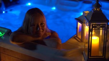 Gece sahnesi. Genç bir kadın çatıdaki jakuzide dinleniyor. Mumlara bakıyor..