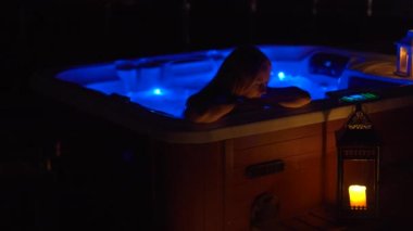 Gece sahnesi. Genç bir kadın çatıdaki jakuzide dinleniyor. Mumlara bakıyor..