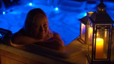 Gece sahnesi. Genç bir kadın çatıdaki jakuzide dinleniyor. Mumlara bakıyor..