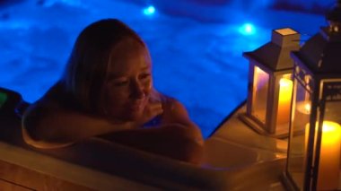 Gece sahnesi. Genç bir kadın çatıdaki jakuzide dinleniyor. Mumlara bakıyor..