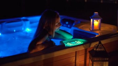 Gece sahnesi. Genç bir kadın çatıdaki jakuzide dinleniyor. Mumlara bakıyor..