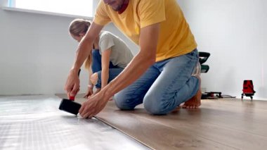 Bir erkek ve bir kadın dairelerinde yere lamine döşüyorlar. Diy konsepti. Yavaş çekim videosu.
