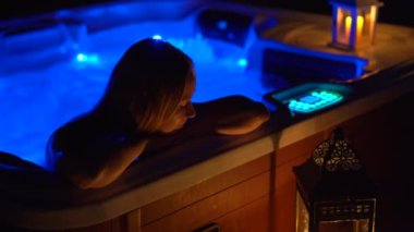 Gece sahnesi. Genç bir kadın çatıdaki jakuzide dinleniyor. Mumlara bakıyor..