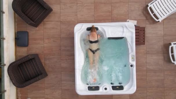 慢动作视频 一位年轻女子在屋顶上的热浴缸里轻松自在地拍着空中照片 — 图库视频影像