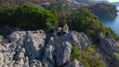 Turist bir aile baba, anne ve oğul bir drone 'la selfie videosu çekiyor. Onlar Budva kenti yakınlarındaki Queens plajında bir kayanın üzerinde oturuyorlar. Karadağ 'a Seyahat.