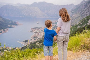 Anne ve oğul gezginler Kotor 'un manzarasından hoşlanırlar. Karadağ. Kotor Körfezi, Kotor Körfezi, Boka Kotorska ve eski şehrin duvarları. Karadağ 'a seyahat. Kotor 'un tahkimatları UNESCO Dünyasında