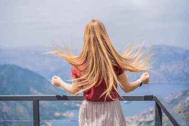 Kadın turist Kotor 'un manzarasından hoşlanıyor. Karadağ. Kotor Körfezi, Kotor Körfezi, Boka Kotorska ve eski şehrin duvarları. Karadağ 'a seyahat. Kotor 'un tahkimatları UNESCO Dünya Mirası' nda.