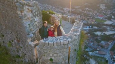 Hava videosu. Anne, baba ve oğuldan oluşan bir turist ailesi dağın tepesindeki Aziz John Kalesi 'nin kulesinde duruyorlar. Şehrin fantastik manzarasının tadını çıkarıyorlar.