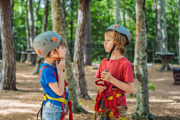 Friends on the ropes course. Young people in safety equipment are obstacles on the road rope.