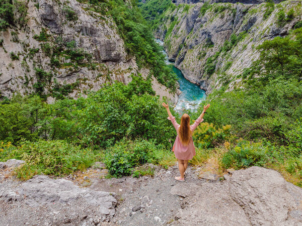 Woman tourist on background of purest waters of the turquoise color of the river Moraca flowing among the canyons. Travel around Montenegro concept.
