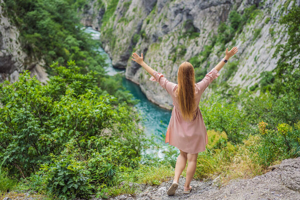 Woman tourist on background of purest waters of the turquoise color of the river Moraca flowing among the canyons. Travel around Montenegro concept.