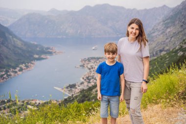 Anne ve oğul gezginler Kotor 'un manzarasından hoşlanırlar. Karadağ. Kotor Körfezi, Kotor Körfezi, Boka Kotorska ve eski şehrin duvarları. Karadağ 'a seyahat. Kotor 'un tahkimatları UNESCO Dünyasında