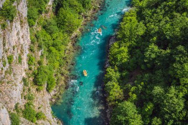 Meşhur rafting ve kano yeri. Renkli can yeleği giymiş aktif kayakçılar kürek çekiyor ve egzersiz yapıyor. Turkuaz nehirde rafting. Karadağ doğası, dağ nehri Tara.