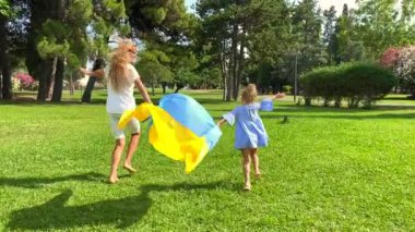 Yavaş çekim videosu. Bir anne ve iki çocuğunun ailesi yeşil krediyle Ukrayna bayrağını taşıyorlar. Mültecilerin desteği. Ukrayna 'nın Restorasyonu.