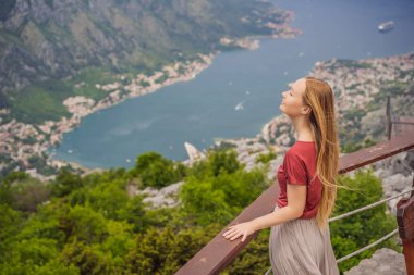 Kadın turist Kotor 'un manzarasından hoşlanıyor. Karadağ. Kotor Körfezi, Kotor Körfezi, Boka Kotorska ve eski şehrin duvarları. Karadağ 'a seyahat. Kotor 'un tahkimatları UNESCO Dünya Mirası' nda.
