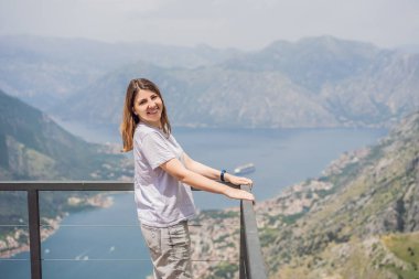 Kadın turist Kotor 'un manzarasından hoşlanıyor. Karadağ. Kotor Körfezi, Kotor Körfezi, Boka Kotorska ve eski şehrin duvarları. Karadağ 'a seyahat. Kotor 'un tahkimatları UNESCO Dünya Mirası' nda.