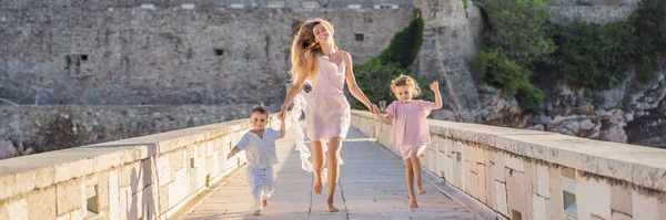 BANNER, LONG FORMAT Mother and two children daughter and son tourists on background of beautiful view St. Stephen island, Sveti Stefan on the Budva Riviera, Budva, Montenegro. Travel to Montenegro