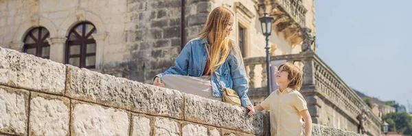 Banner, eski anne ve oğul turistler güneşli bir günde Karadağ 'ın eski Perast kasabasında renkli caddelerin tadını çıkarıyorlar. Karadağ 'a seyahat. Tarihi Perast kasabasının manzaralı manzarası