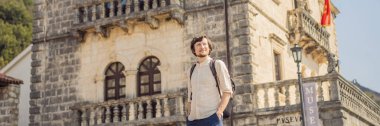 BANNER, BANNONG eski erkek turist güneşli bir günde Eski Perast kasabasında renkli caddenin tadını çıkarıyor. Karadağ 'a seyahat. Ünlü tarihi Perast kasabasının manzara manzarası.